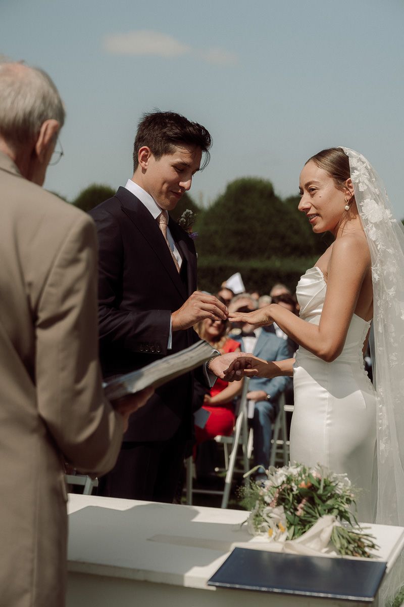 A series of wedding ceremony photos showing the exchange of rings during an outdoor summer celebration at Birtsmorten Court