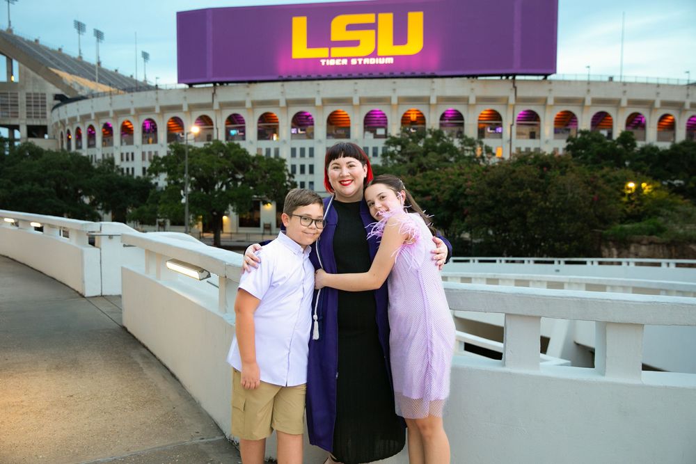 LSU graduate celebrating with family in front of the LSU marquee