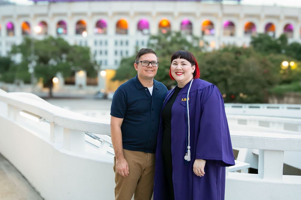 LSU graduate celebrating with family in front of the LSU marquee