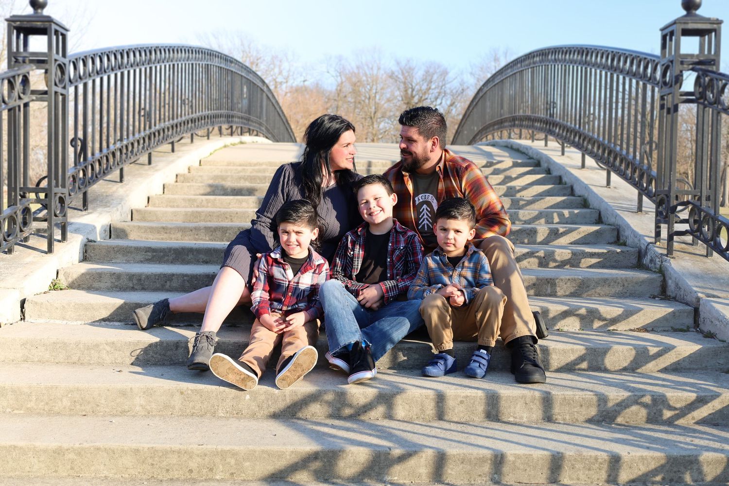 Group sitting together on decorative stone bridge steps during outdoor photo session.
