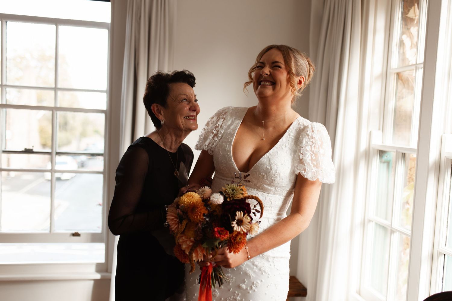 Four women laughing and socializing together in a bright indoor setting.