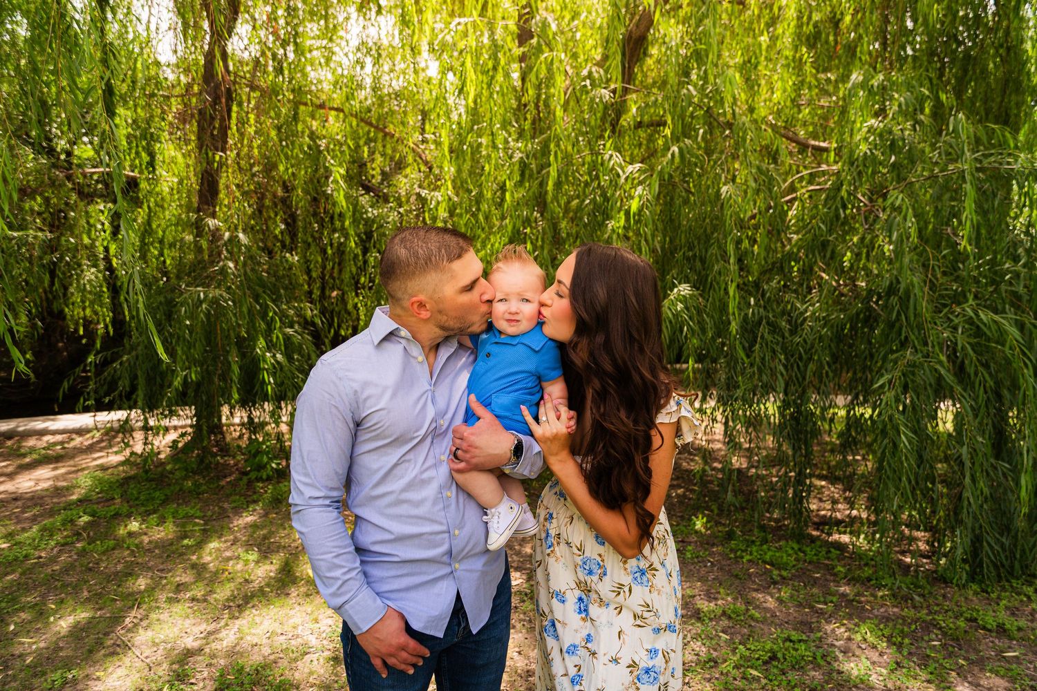 A couple shares an intimate moment under cascading willow branches in a romantic outdoor setting. Engagement session fort worth texas