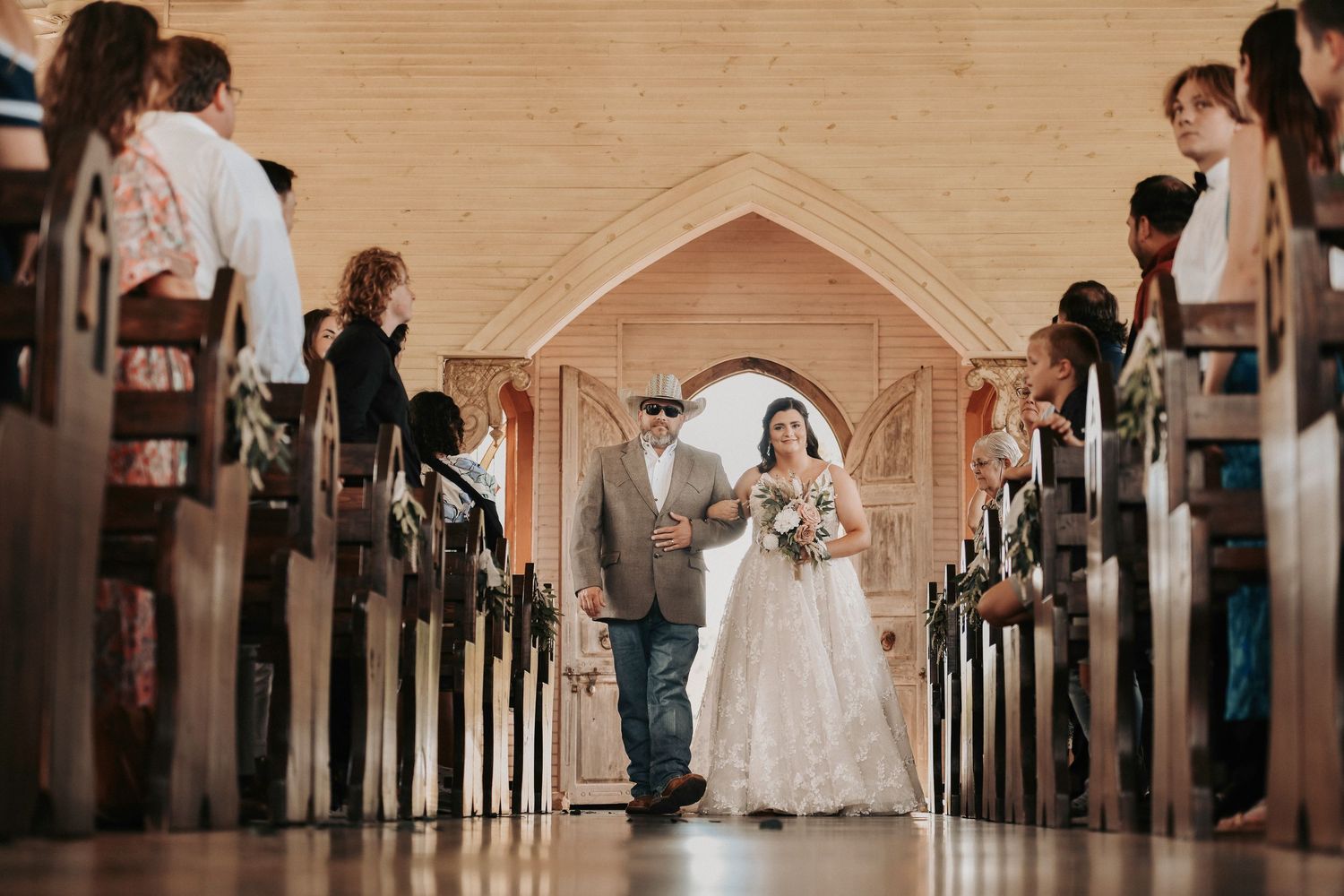 Classic chapel wedding ceremony with bride walking down aisle toward groom