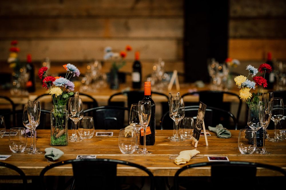 Elegant table settings with wine glasses and small flower arrangements on a rustic wooden dining table.