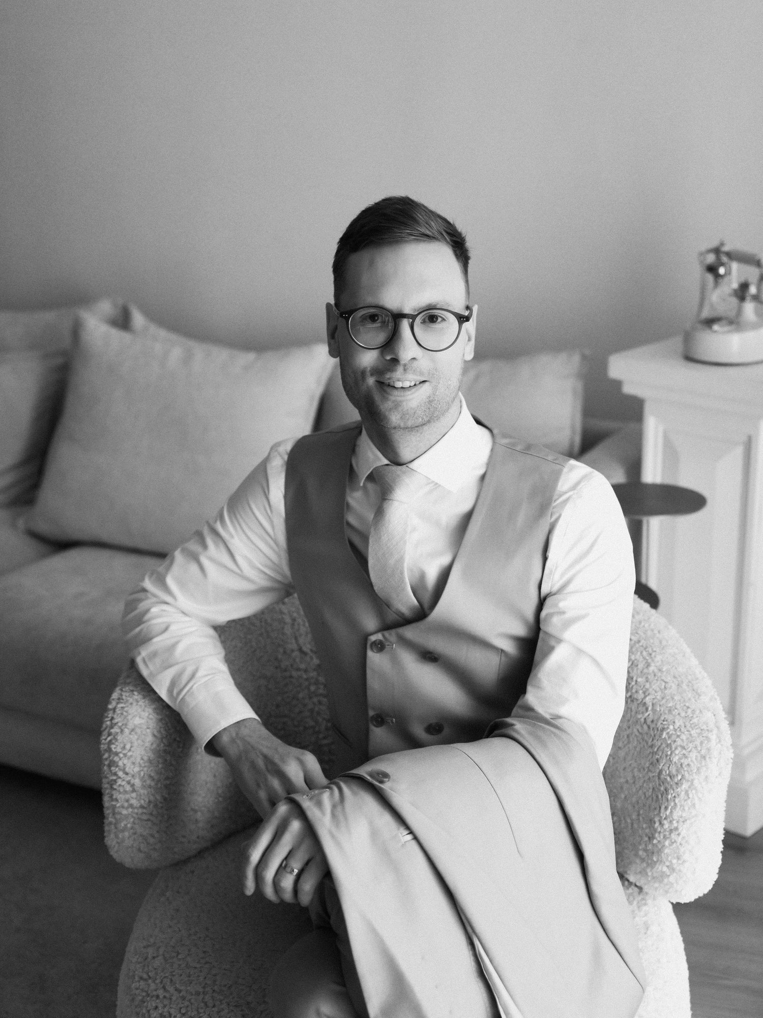 Black and white portrait series of a person in glasses and white shirt lounging on a couch.