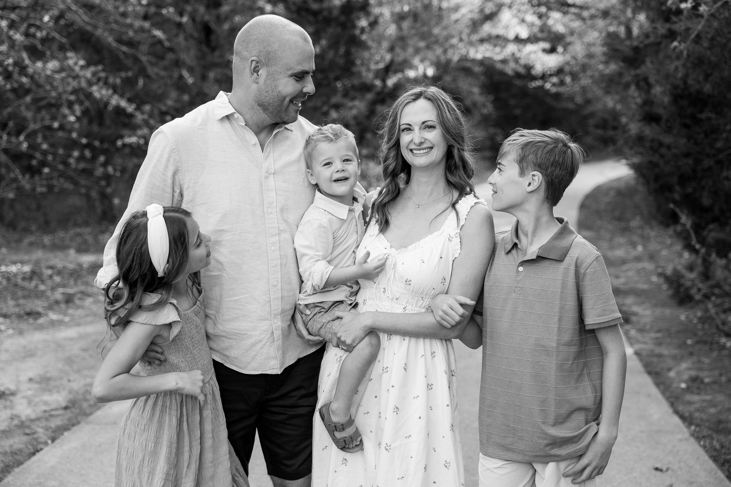 A happy family shares joyful moments together while walking outdoors in black and white photography.