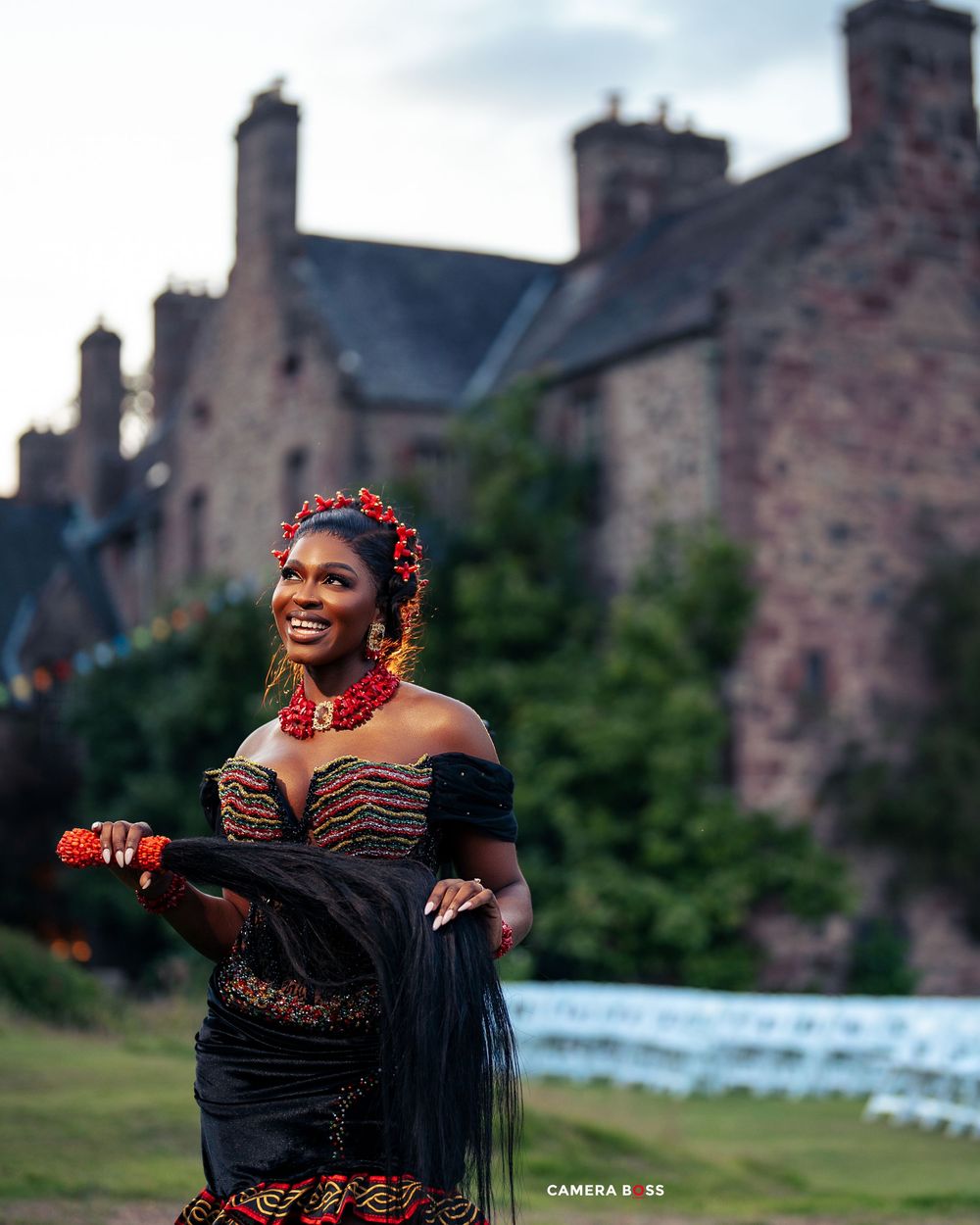 Dancer in a black dress with red accents performs gracefully against a backdrop of historic stone buildings.