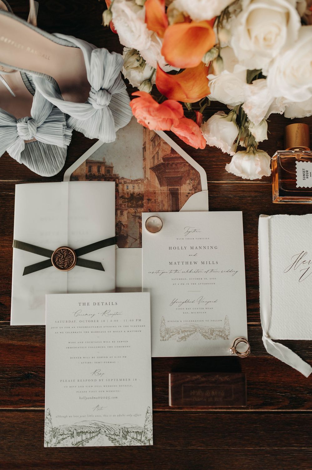 Elegant wedding invitation suite with wax seal, orange florals, and gold rings.
