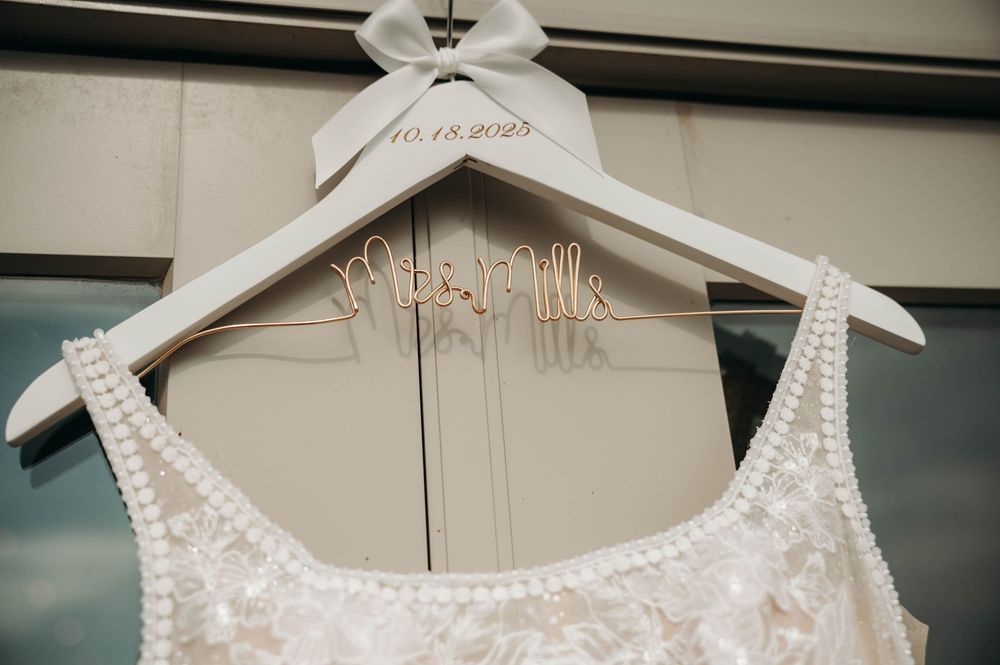 Personalized white wedding dress hanger reading Mrs. Hills with date 10.18.2024 on pearl-trimmed gown.