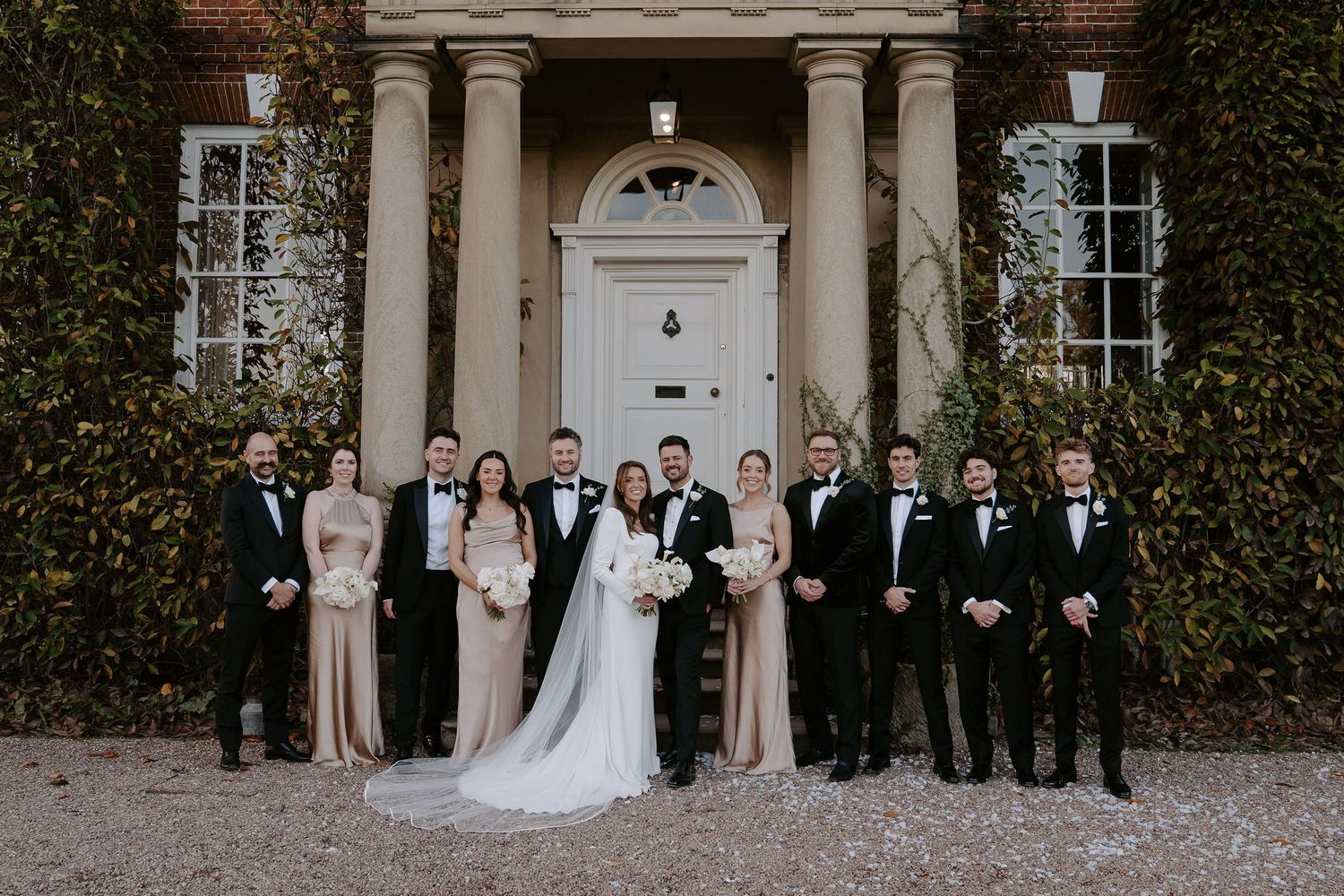 bride and groom and wedding party smiling for a portrait outside Iscoyd park