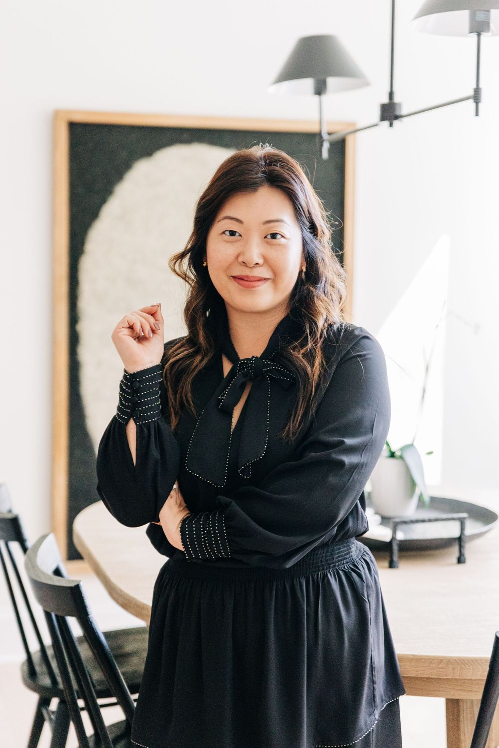 A person wearing a black dress poses playfully in different positions against a light interior background.
