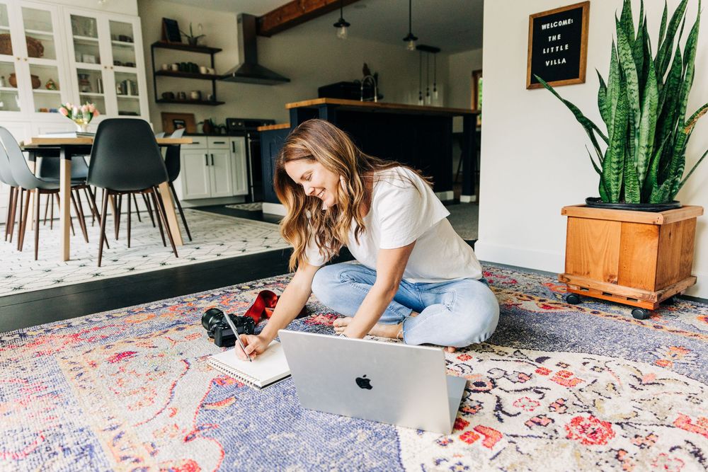 A woman sits on a floor with her laptop doing some work during Charlotte branding photo session.