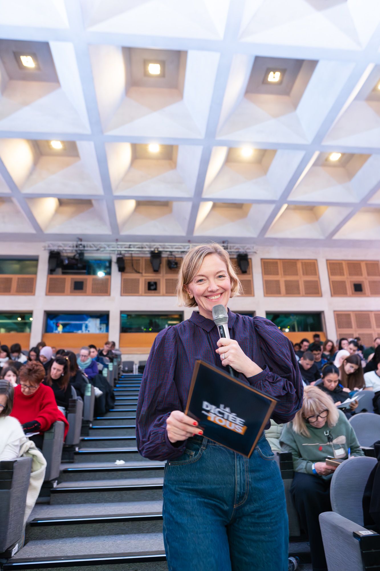 A sequence of photos showing a person in casual attire posing with a mobile device in a lecture hall setting.