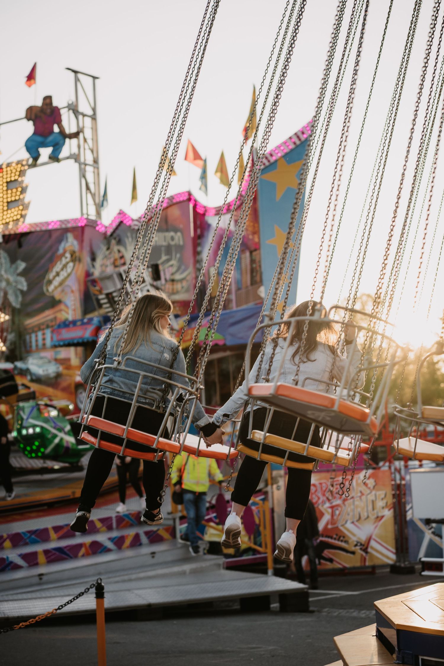Carnival swing ride seats photographed at sunset with warm golden light creating a nostalgic amusement park atmosphere.