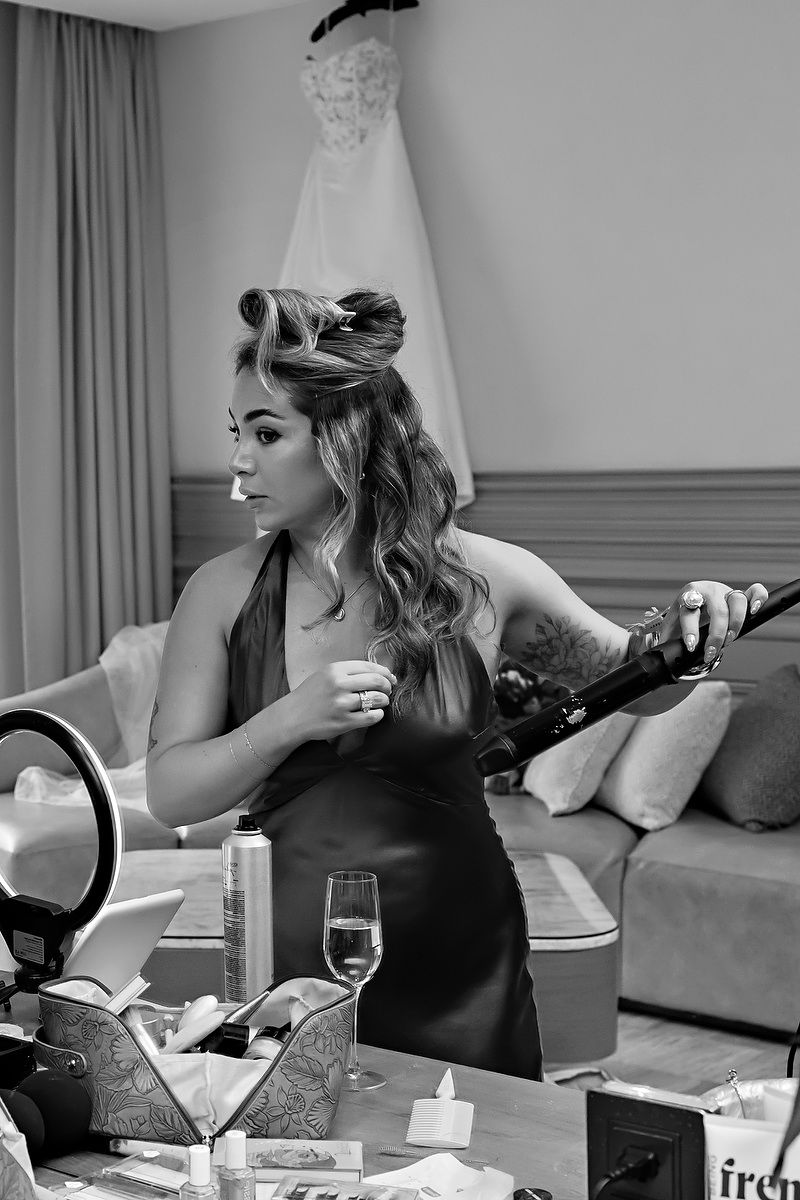 Black and white photo series showing a person in a dark dress sitting at a dining table with wine glasses and decor.