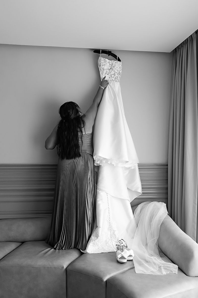 A series of black and white photos showing a wedding dress hanging against a gray wall in different compositions.