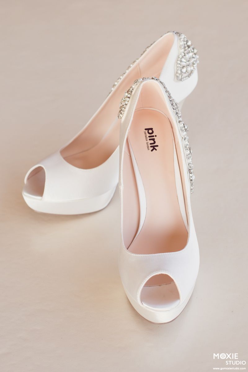 Elegant white satin peep-toe wedding heels with crystal embellishments on the back heel.