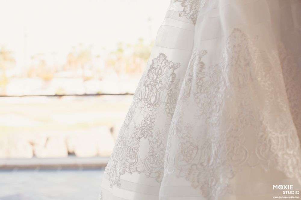Close-up view of delicate white lace wedding dress fabric with intricate floral patterns and embroidery details.