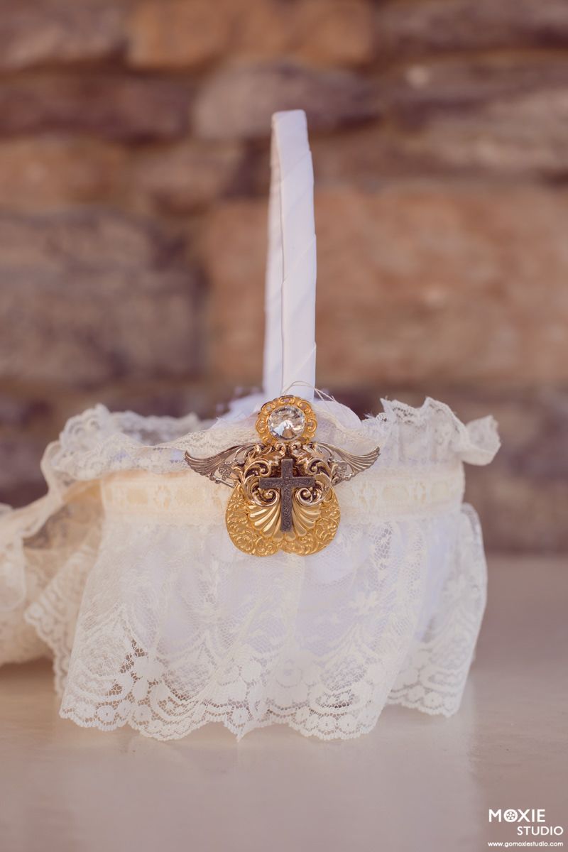 Delicate white lace garter with gold owl charm detail displayed against rustic stone background.