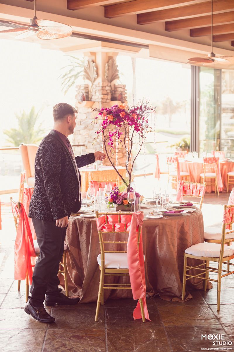 Wedding reception venue with coral linens and brown tablecloths being set up in a sunlit room.