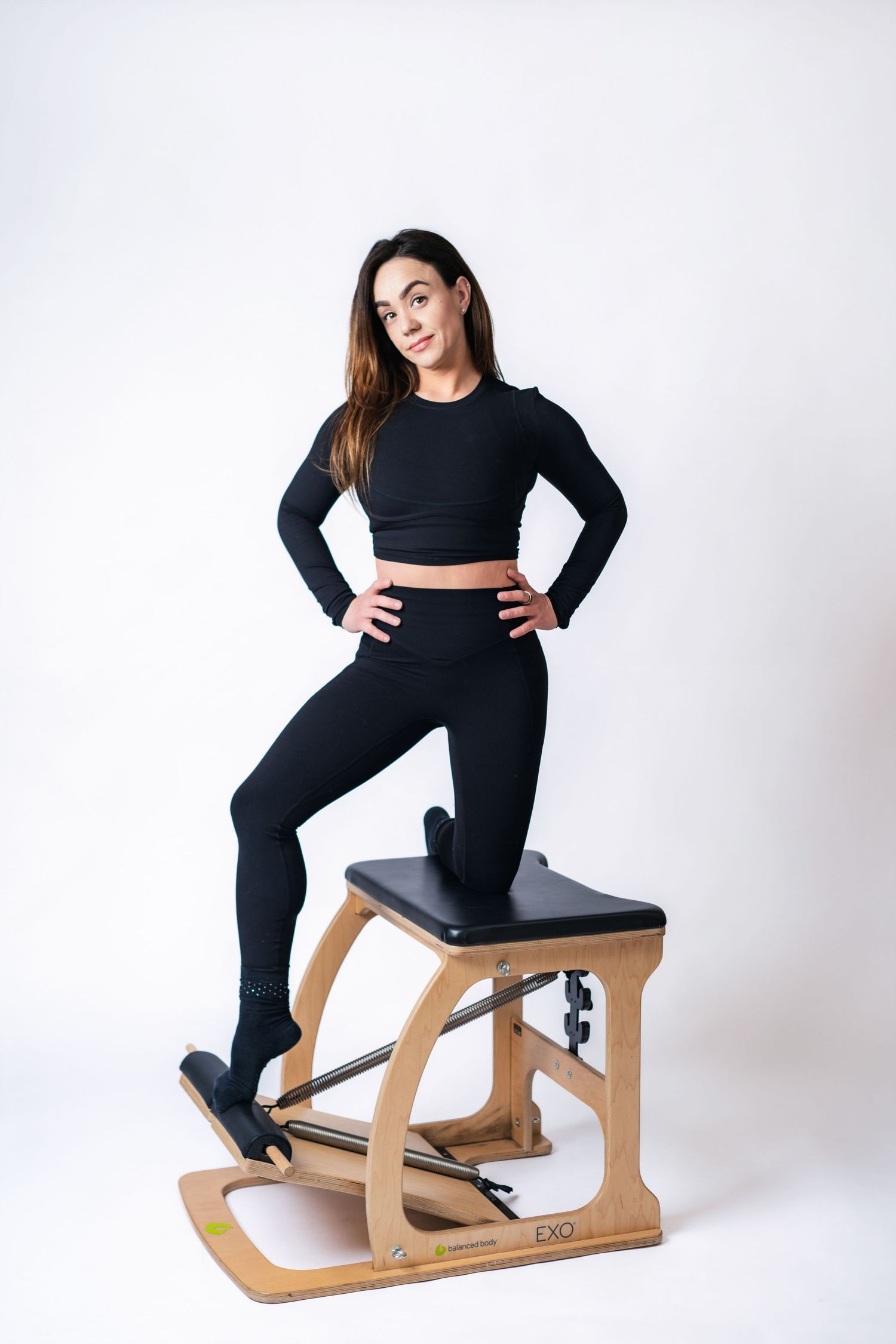 Ergonomic wooden kneeling chair shown from three angles with model demonstrating proper posture in black outfit.