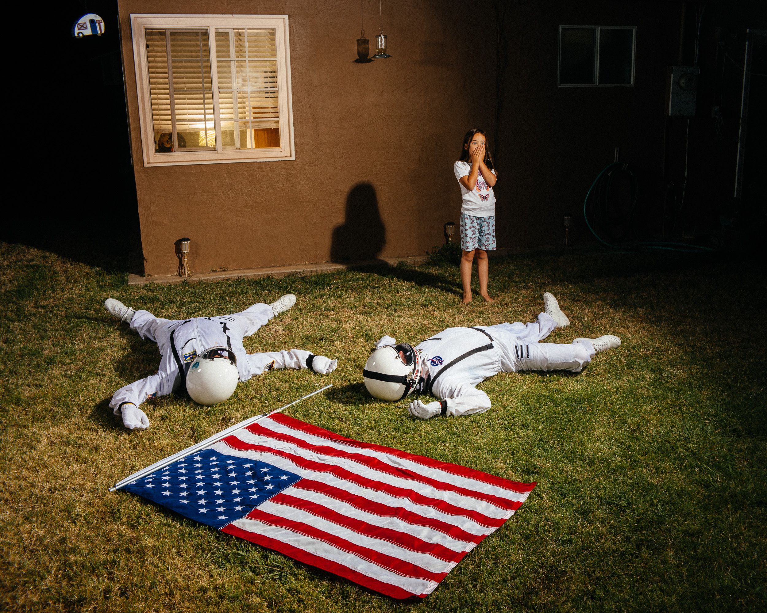 A person lies on the ground with an American flag on grass in a sequence of eight progressive motion photographs.