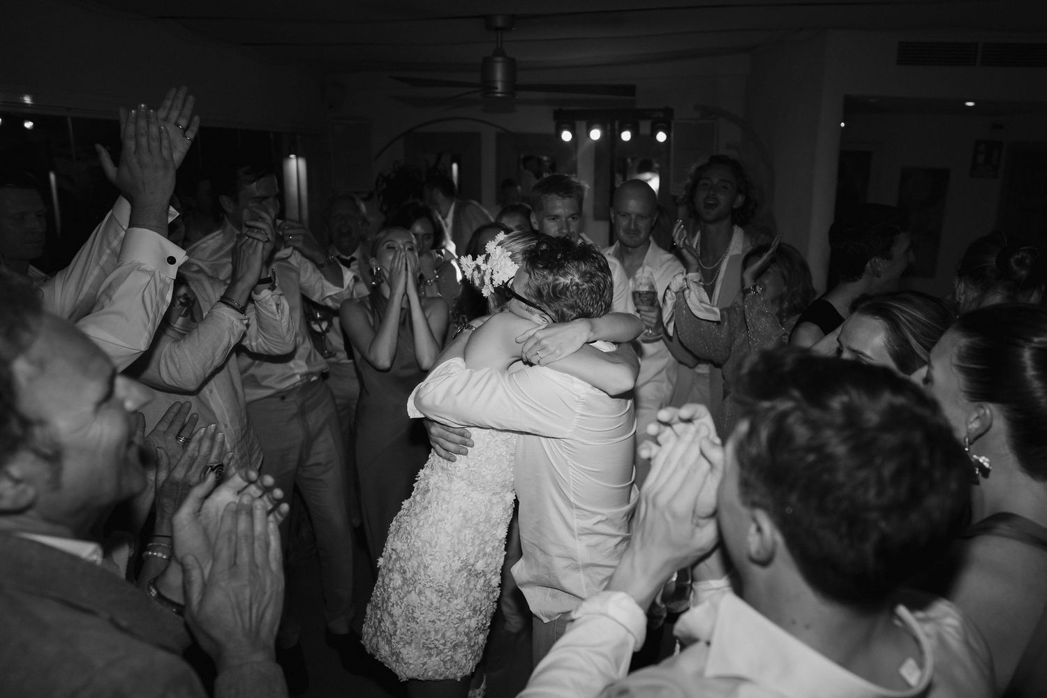 bride and groom embracing while wedding guests cheer and clap during party at amante ibiza