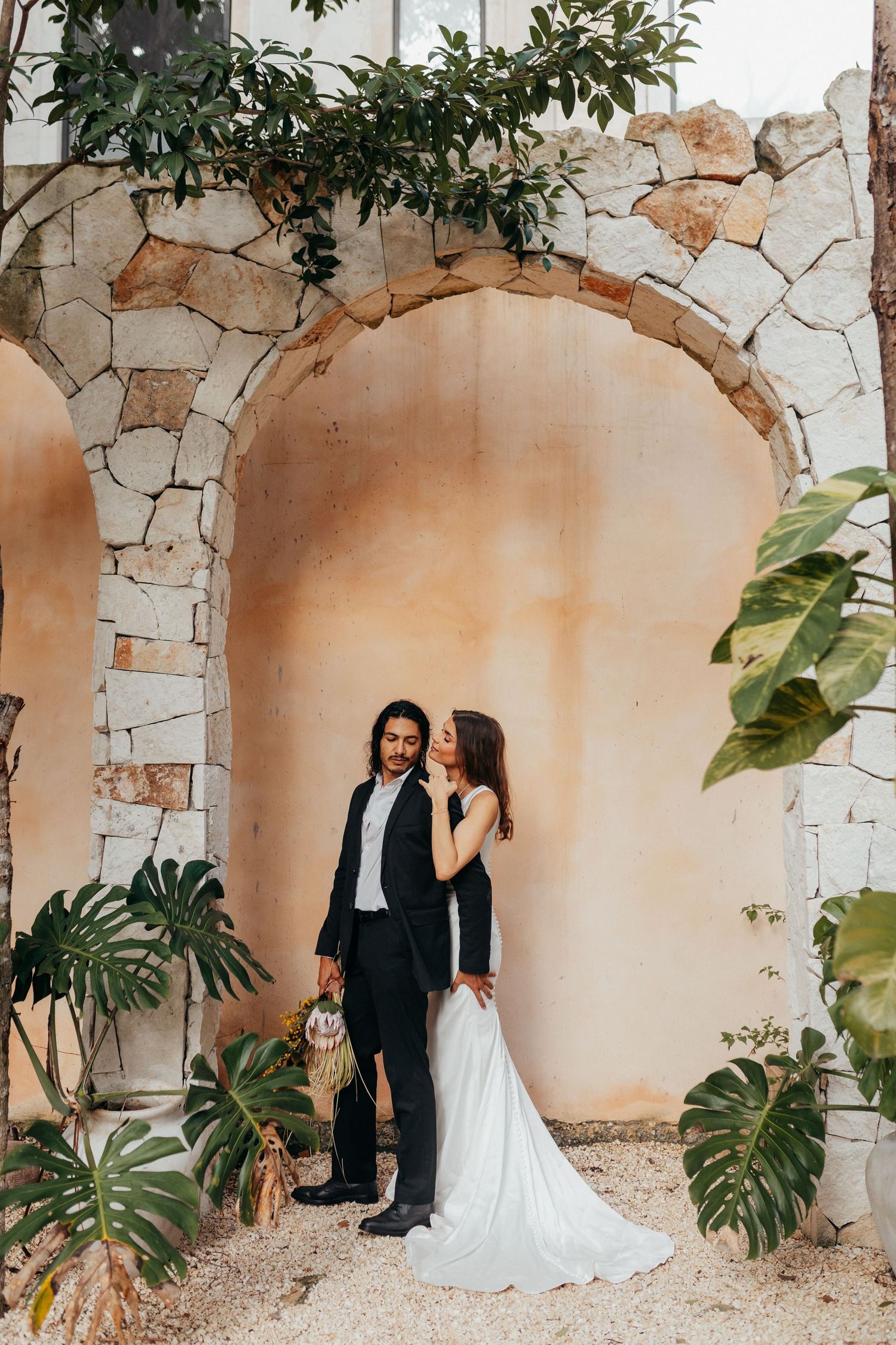 Romantic sunset wedding photoshoot in a rolling Tuscan landscape with cypress trees lining a winding path.