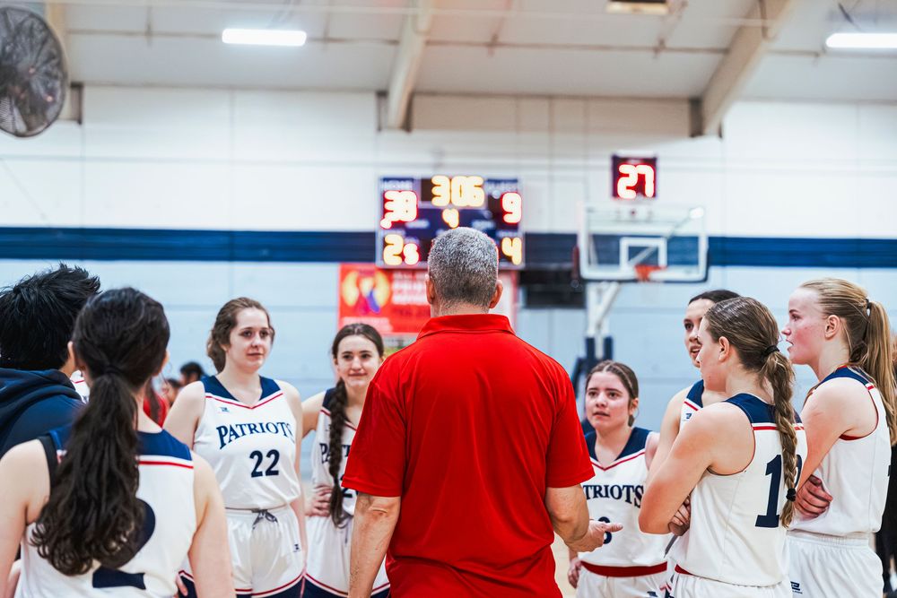 Coach talking to players in a huddle with the score in front