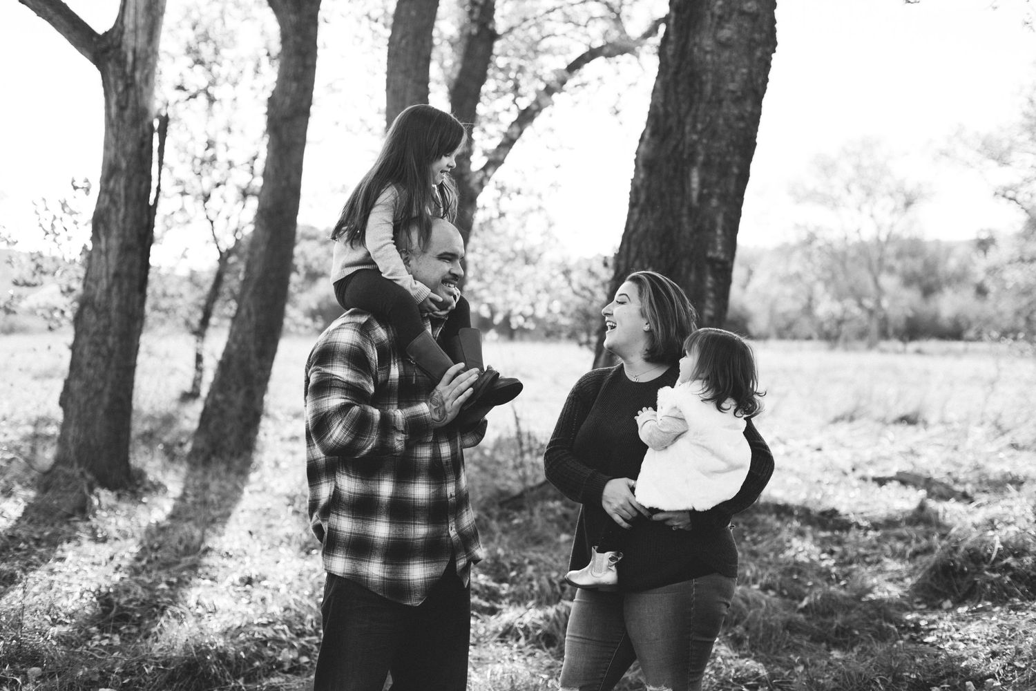 Candid black-and-white moment of a family session under the oak trees, capturing connection and warmth in a natural setting.