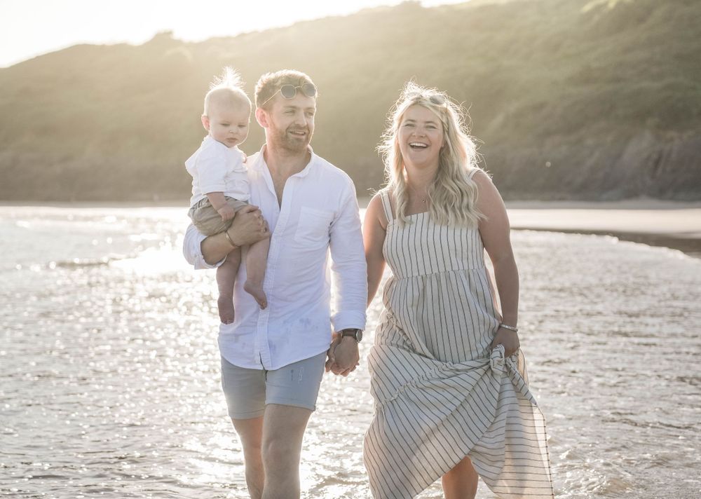 Family walking along shoreline during golden hour at the beach.