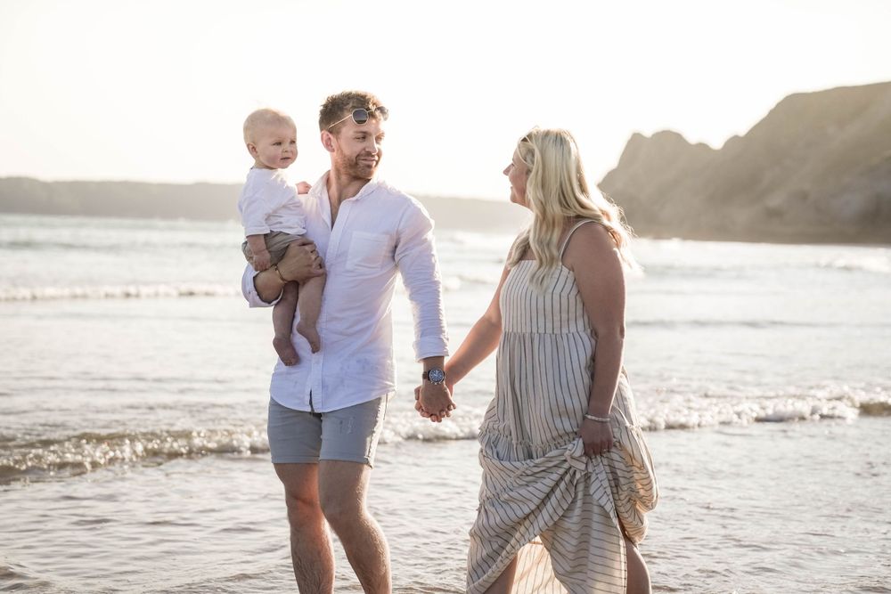 Family playing and laughing together on beach at sunset.