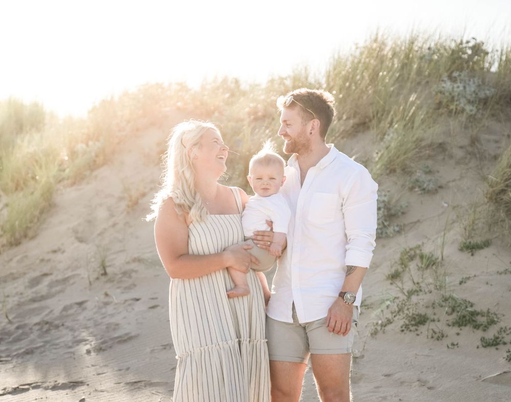 Family sharing joyful moments among sandy dunes at sunset.