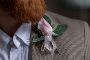 Delicate pink rose boutonniere pinned to formal grey suit.