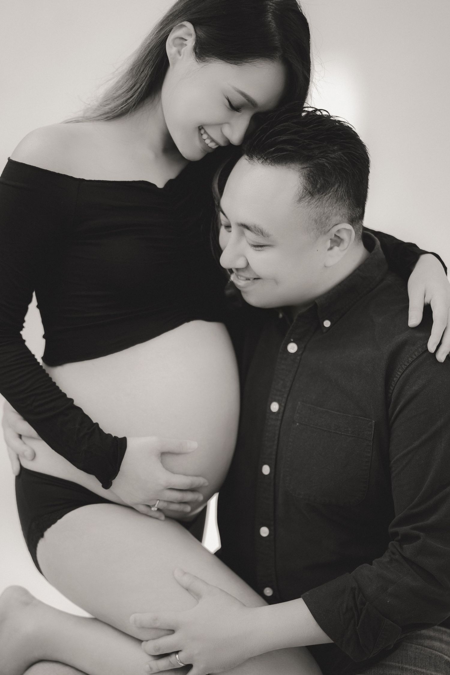 Ethereal maternity photo with soft white draping fabric and natural window light illuminating a peaceful bedroom scene.