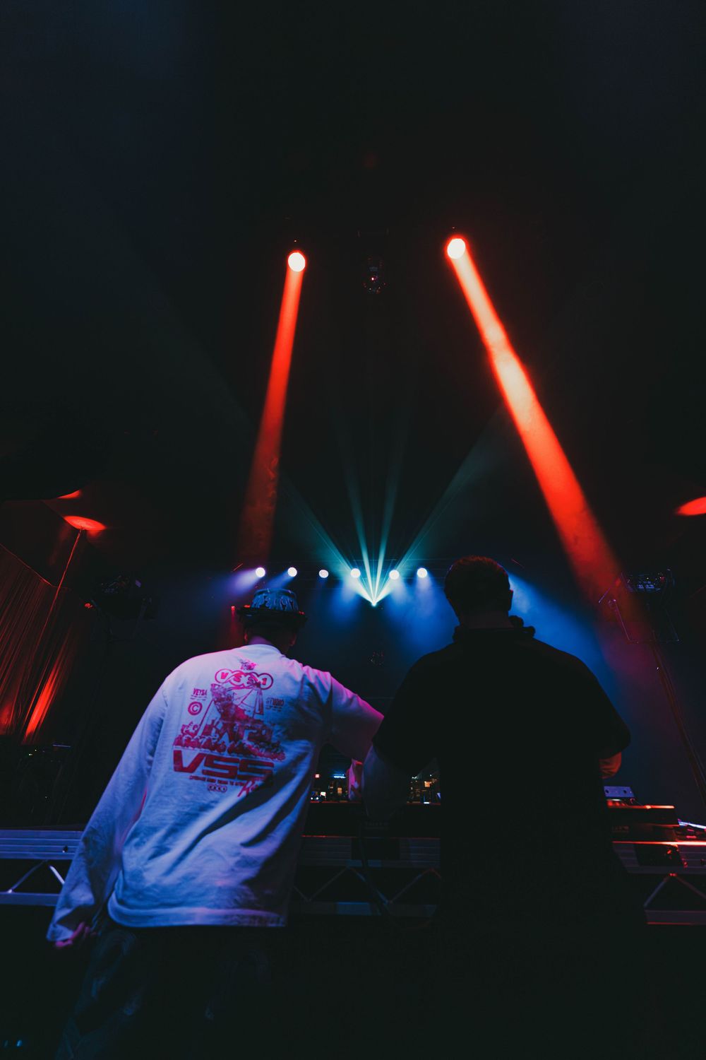 Concert stage illuminated with dramatic red and blue spotlights during a live performance at night.