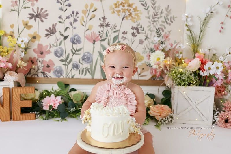 Baby celebrating birthday with strawberry themed decor and pink balloon arch.