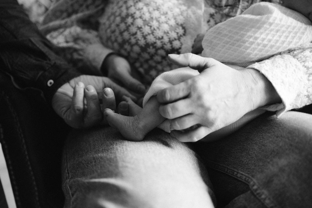Black and white close-up photograph of hands gently clasped together on a lap.