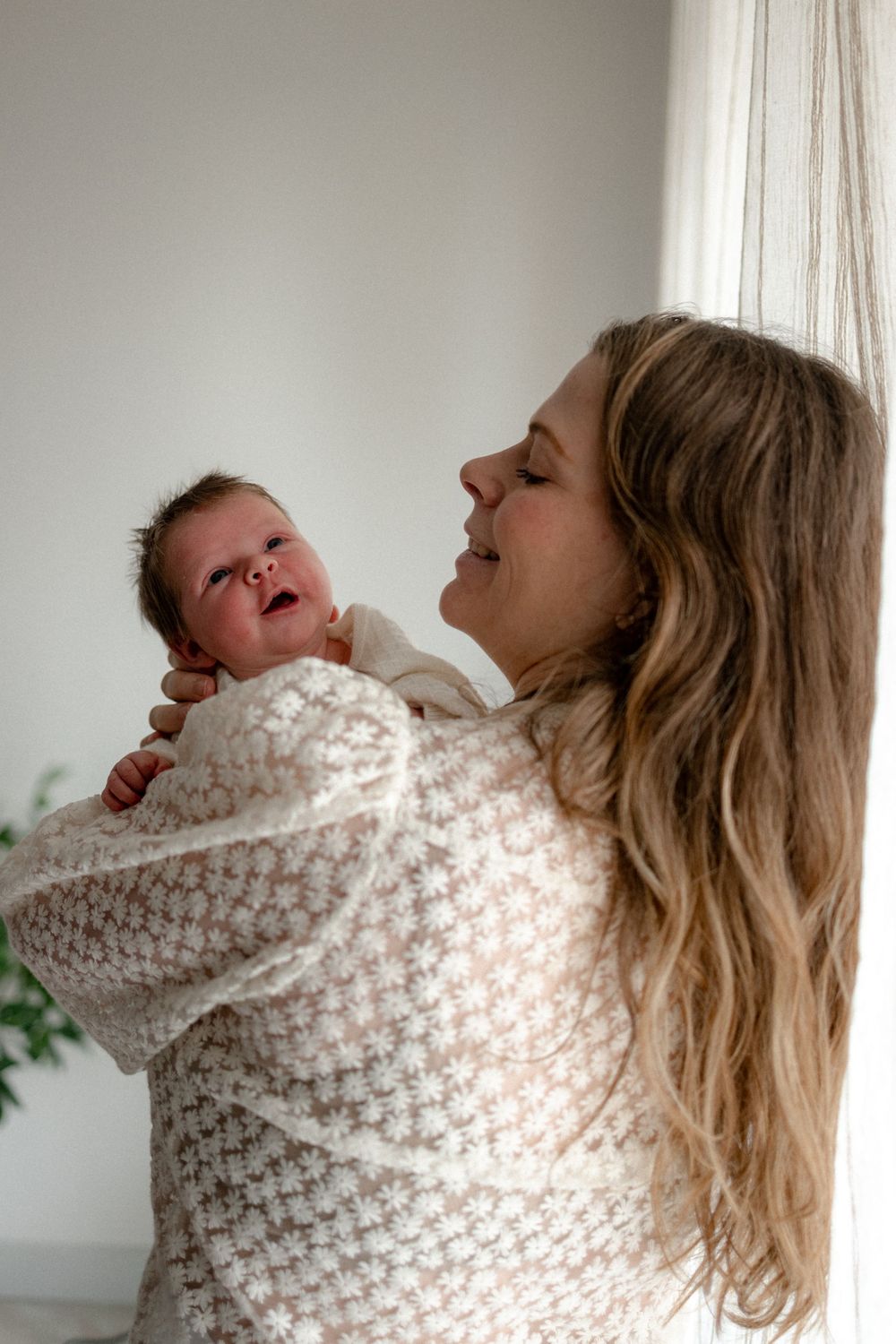 A series of five candid photos showing joyful laughter and interaction between a parent and baby in white knit clothing.