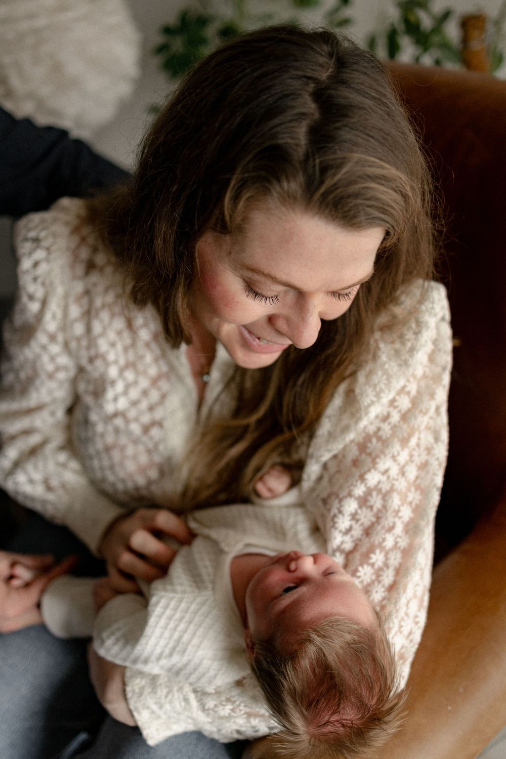 A tender moment captured in a series of photos showing a parent in a white sweater cradling and bonding with a newborn.