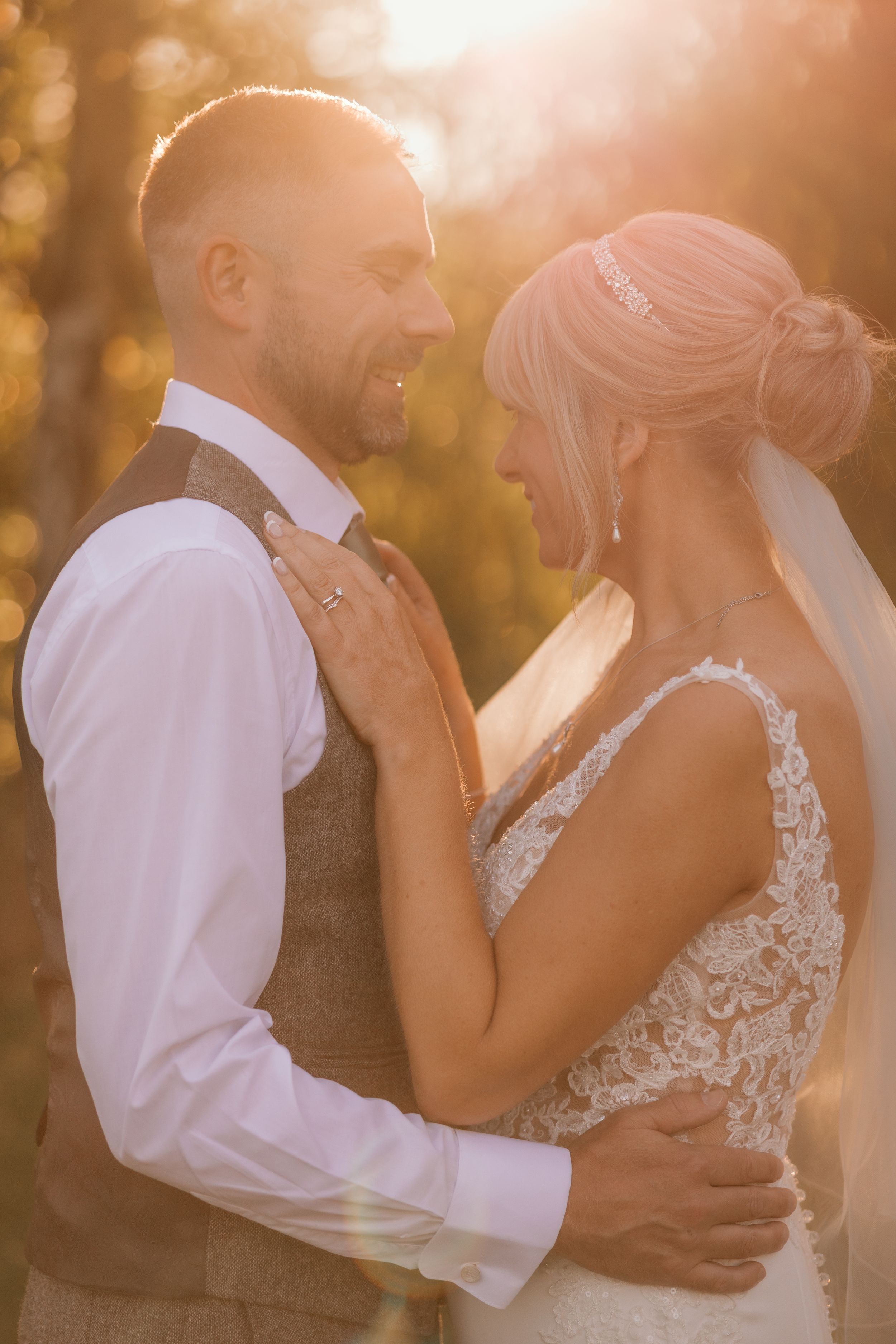 Romantic sunset portrait of newlyweds embracing in golden light.