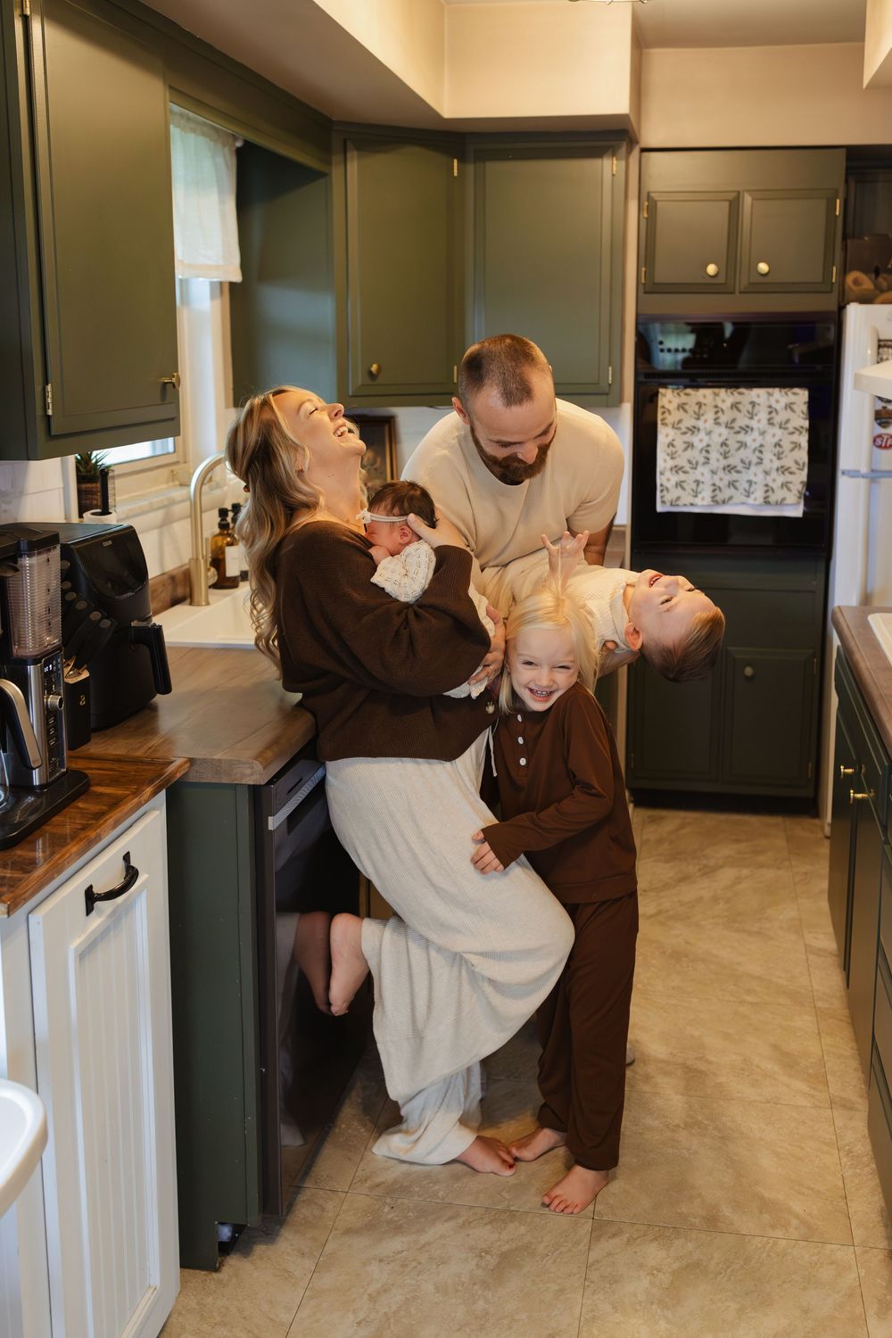 Playful dance scene in a modern kitchen with green cabinets.