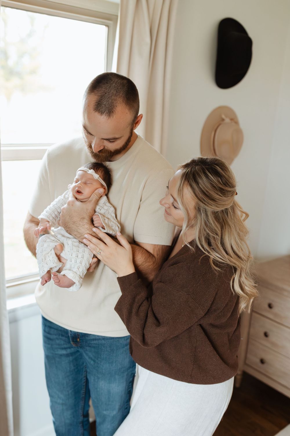 Candid family moment captured in a bright bedroom with natural light.