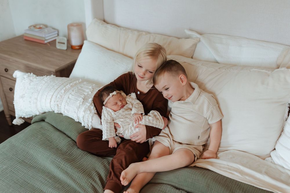 Intimate family portrait session on a white couch with soft natural lighting.