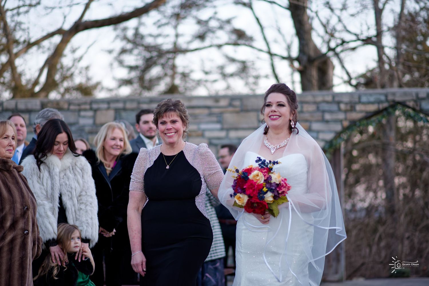 Winter wedding celebration with bride and mother walking down the aisle outdoors.