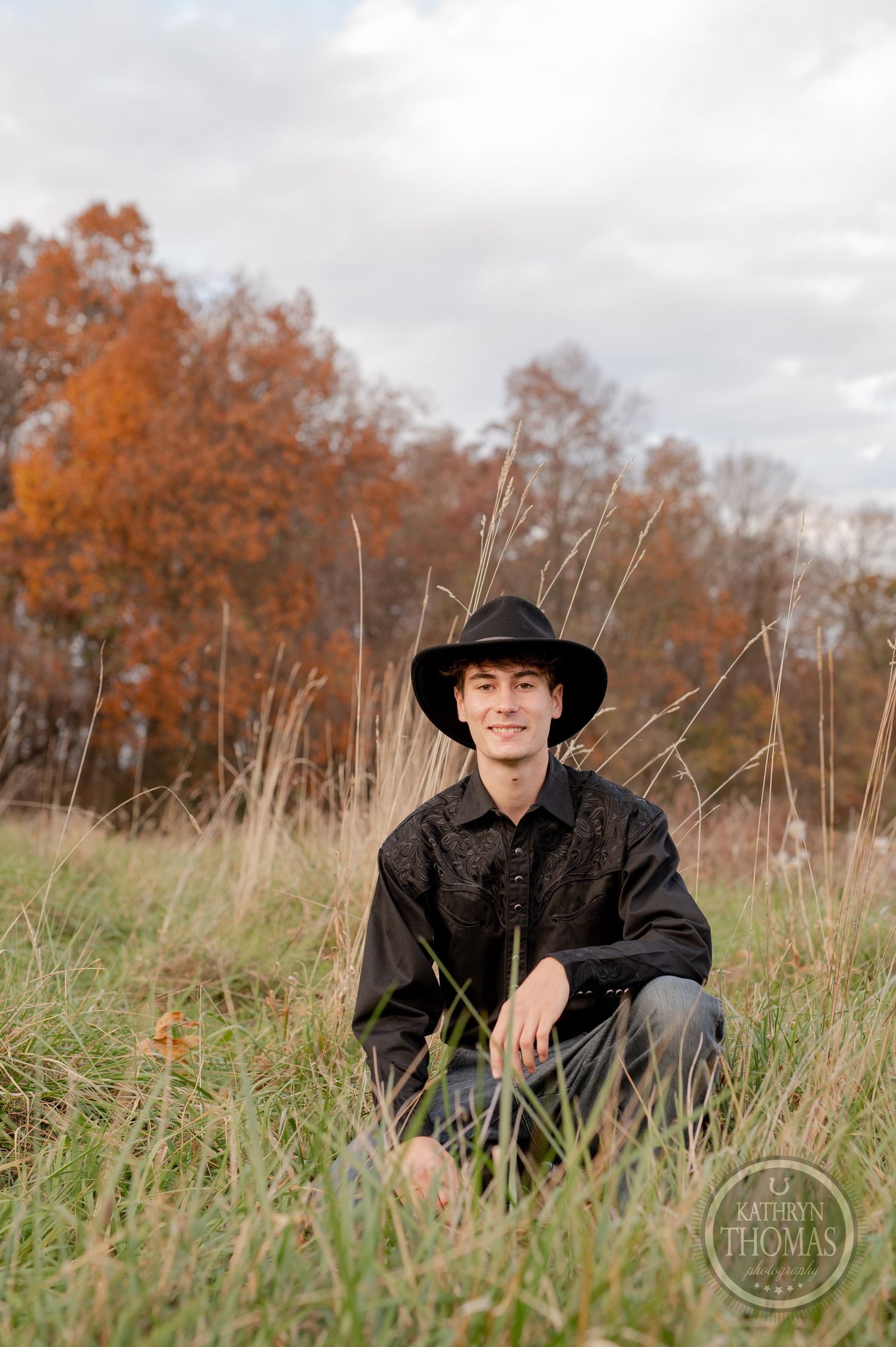 Autumn outdoor portrait with tall grass and orange foliage in the rural background.