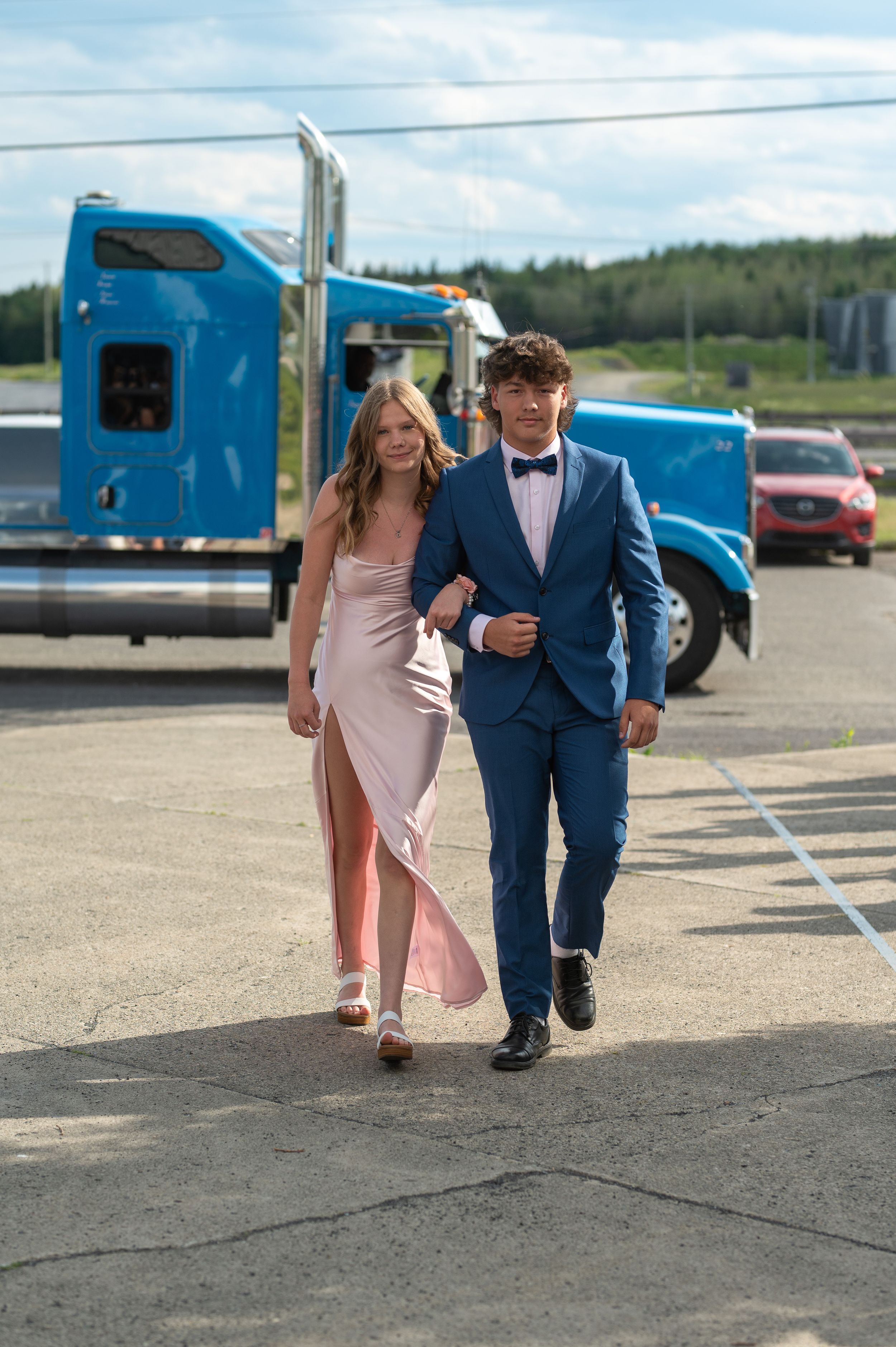 A couple walks through a parking lot with a blue truck in the background.