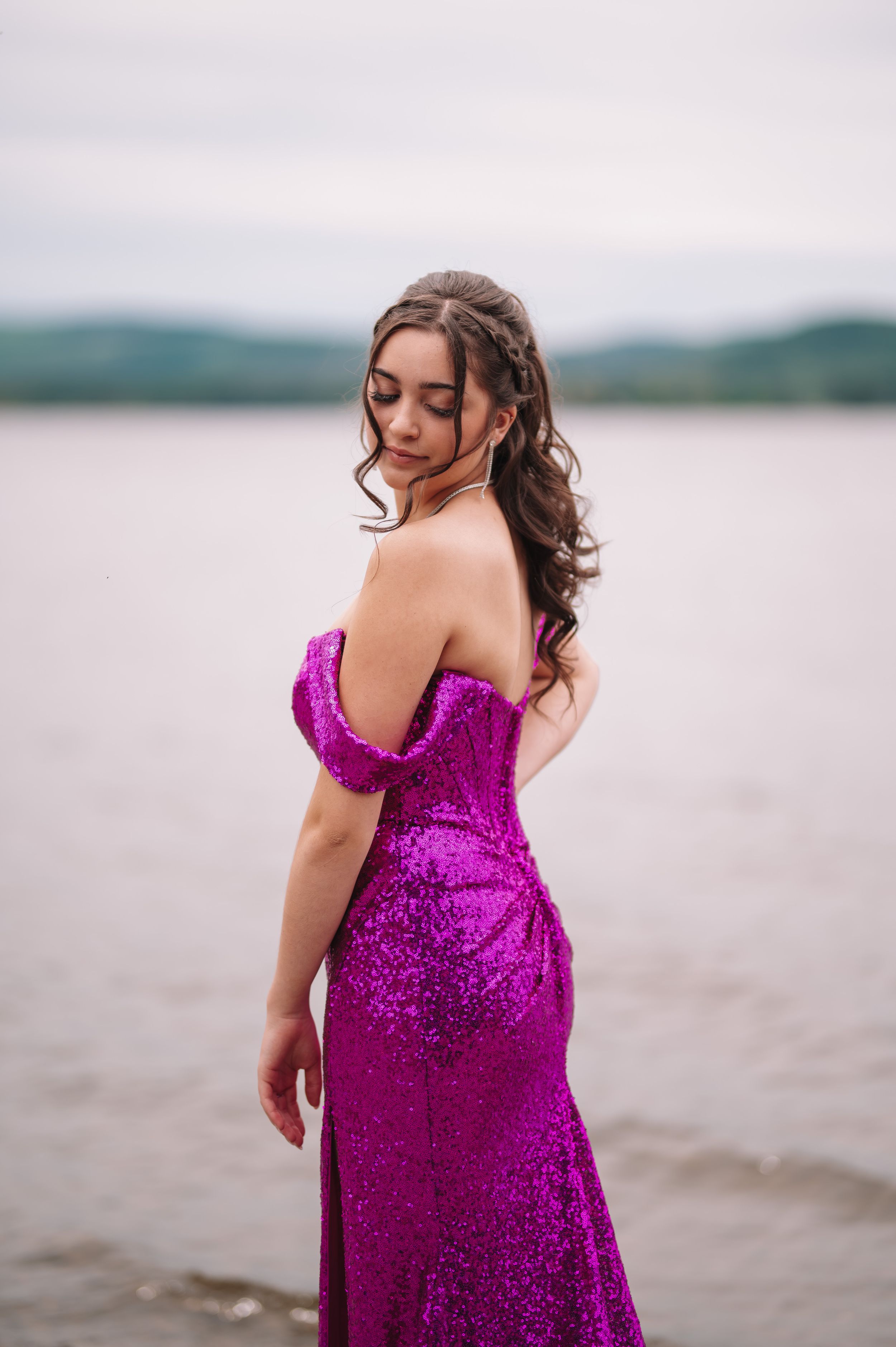 A sparkly magenta evening gown photographed against a lakeside backdrop.