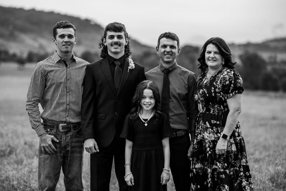 Black and white family portrait of five people in countryside setting.