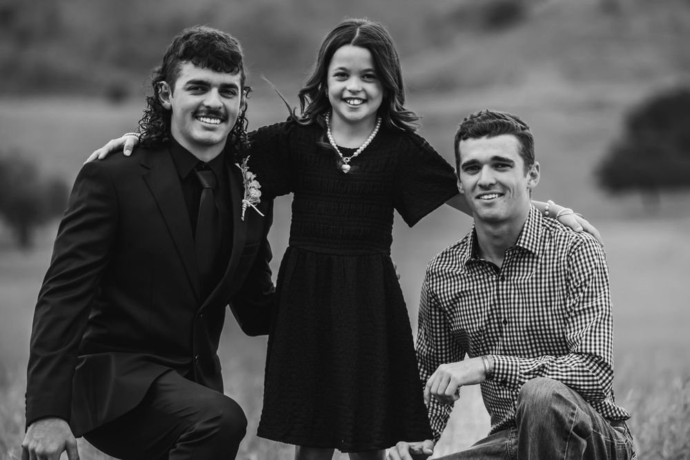 Three people sharing a candid moment together outdoors in black and white photography.